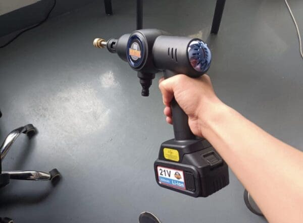 A person holding an electric drill in their hand.