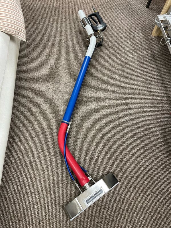 Carpet cleaning wand on brown carpet.